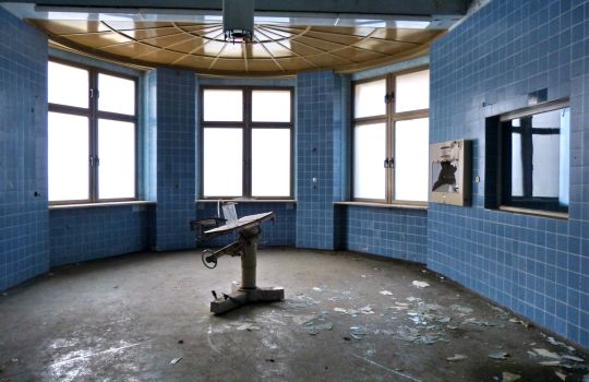 Runder, verlassener Raum mit blauen Fliesen.